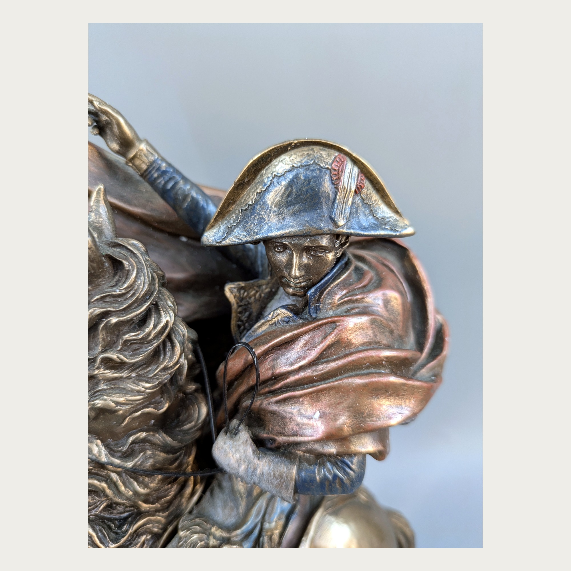 Detail of Napoleon face, bicorne hat, and red-brown cloak on the statue