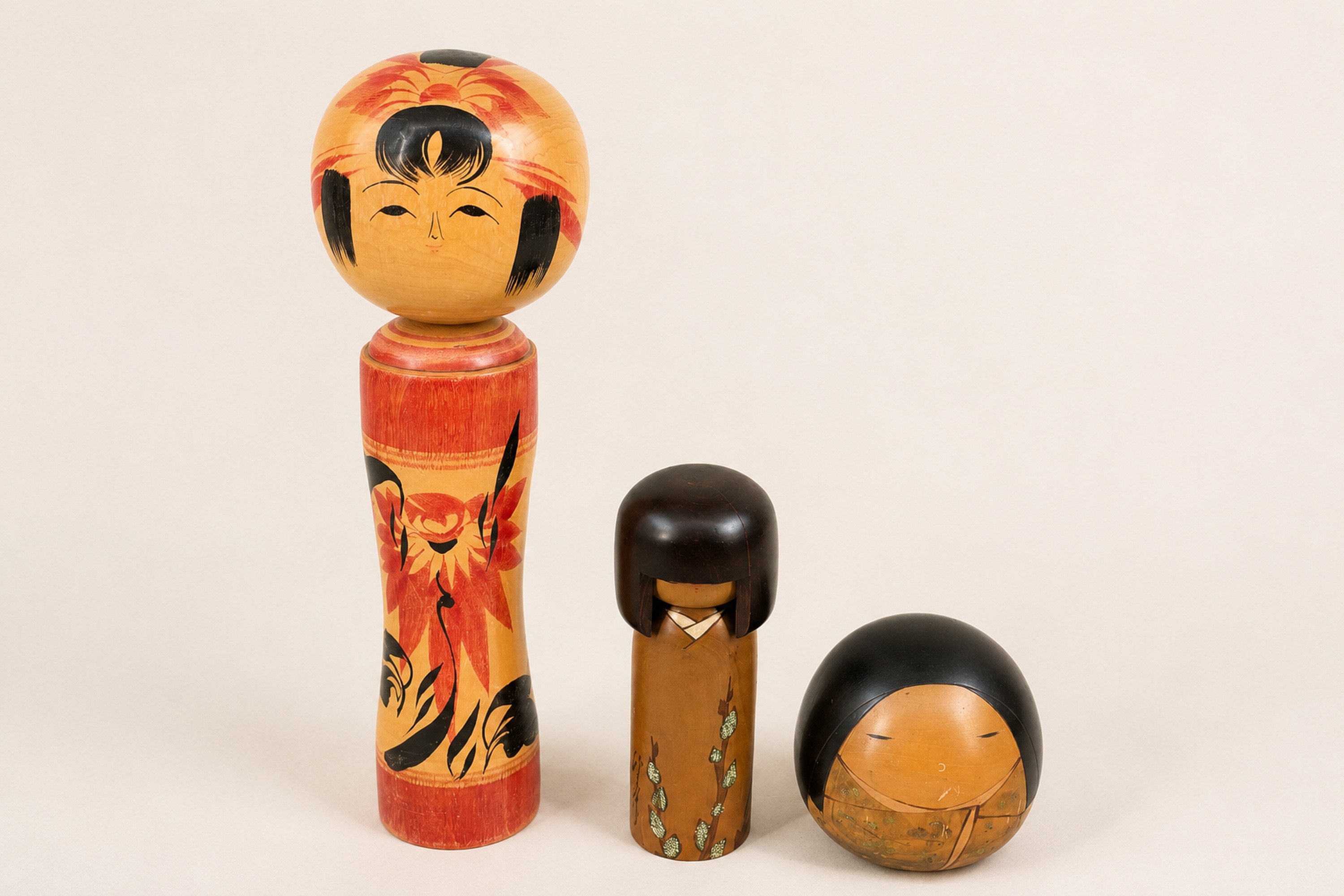 Three Japanese painted wooden dolls photographed together